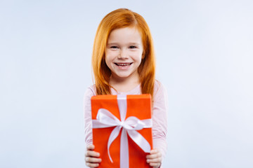 Wonderful surprise. Cheerful red haired girl smiling while giving you a present