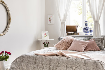 Soft gray and lemonade pink bedding and pillows on a bed which is standing against a bright window...