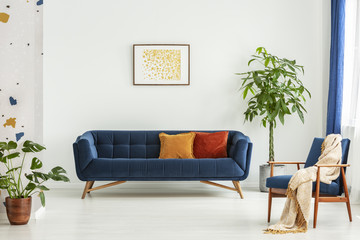 Mid-century modern chair with a blanket and a large sofa with colorful cushions in a spacious...