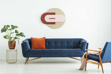 Creative geometric art on a white wall above an elegant blue sofa in a mid-century modern style...