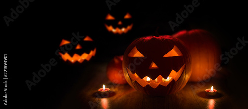 halloween and holidays concept - many spooky carved pumpkin jack-o-lanterns with candles in darkness