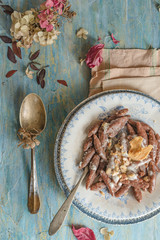 dried pears flour gnocchi seasoned with parmesan cream.  Autumn leaves and hydrangea flower scattered on a rustic wooden base. Top view 
