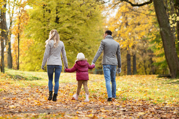 Obraz premium family, season and people concept - happy mother, father and little daughter walking at autumn park