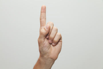 Male hand holding up index finger, one number gesture, showing up
