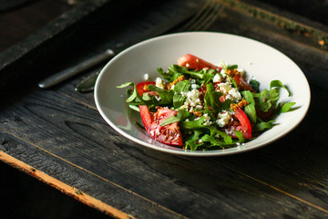vegetable salad with rucola, tomato and other vegetables in a white plate. Top view rosemary. food background