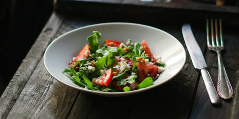 vegetable salad with rucola, tomato and other vegetables in a white plate. Top view rosemary. food background