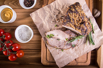 Piece and slices of roasted meat. Cold-boiled baked pork with mustard grains on wooden background.