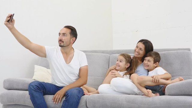 Cheerful family with children laughing taking selfie together on phone