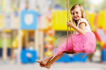 Little child blond girl having fun on a swing