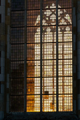 Last sunlight from the setting sun radiates atmospherically through stained glass windows of an old gothic church in a historic old fortified town in the Netherlands 