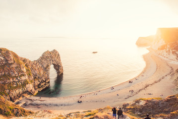 Fototapeta na wymiar Landscape of Durdle Door with all over the world intarnational turists joining view of Sunset. Dorset, England. Selective focus. Copy space.