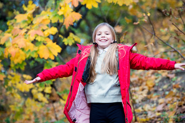 Free and happy cutie. Child blonde long hair walking in warm jacket outdoor. Girl happy in red coat...