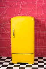 Bright yellow refrigerator in pink interior. Retro fridge looks awesome in modern interior. Stylish interior details. Original household appliances. Pop art concept. Vintage household appliances