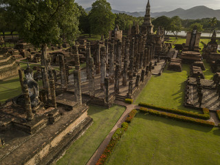 Fototapeta na wymiar Aerial View of a historical sites ruins Buddhist Temple Wat Mahathat at The Sukhothai Historical Park, a registered UNESCO World Heritage City in the tranquil late afternoon sun