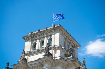 european union flags waving in the wind at famous Reichstag building, seat of the German Parliament (Deutscher Bundestag), on a sunny day with blue sky clouds, central Berlin Mitte district, Germany