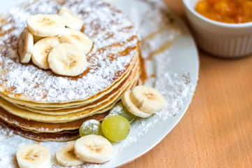 Stack of pancakes with banana, grapes and caramel