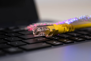 Yellow internet switch , glowing optical fibres, close up macro shot on laptop computer keyboard,...