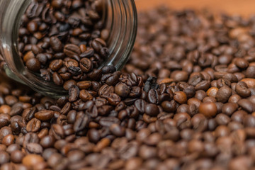 Coffee beans, poured from a glass transparent jar.