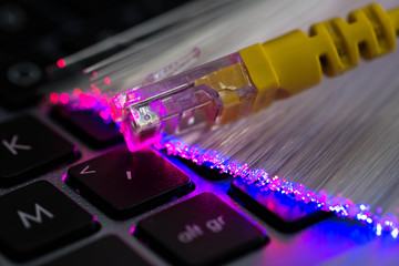 Yellow internet switch , glowing optical fibres, close up macro shot on laptop computer keyboard,...