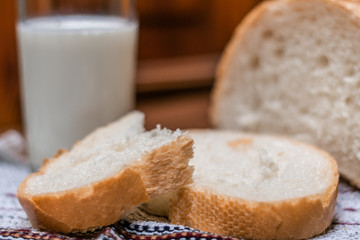 A glass of milk and bread on a wooden table.