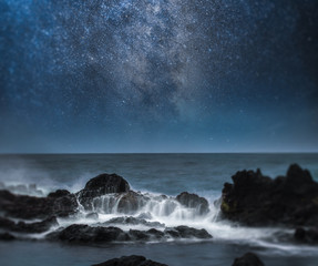  a starry night sky over the ocean.