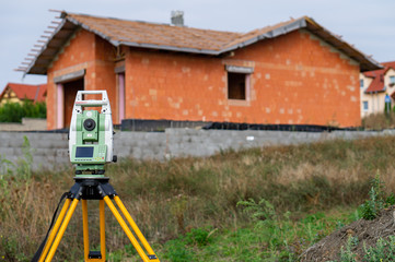 Surveyor equipment (theodolit) on construction site with house and sky  in background