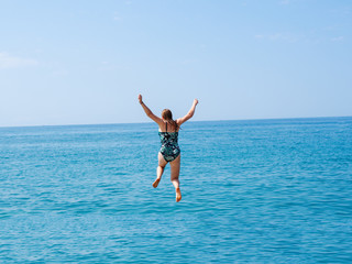 Young woman jumping into the sea