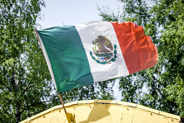 Mexican flag on a yellow building waving