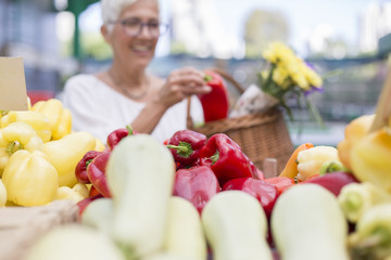 Good-looking senior woman wearing glasses buys pepper on market