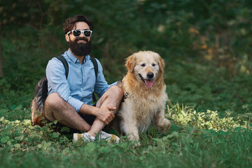 Man resting on the grass sitting crossed legs with his dog