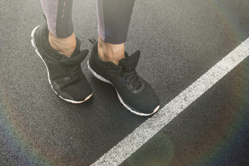 Athlete in black sneakers stands in front of the white start line