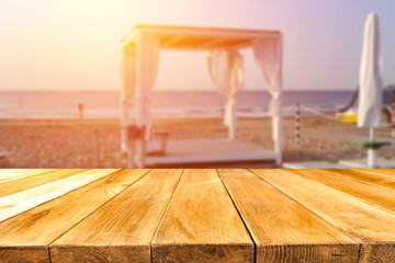 old wooden table on the beach at sunset in golden tone  