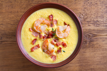 Creamy corn vegetable soup with shrimps and bacon. View from above, top studio shot