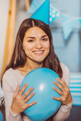 Ready for holiday. Attractive merry woman embracing balloon while smiling to camera