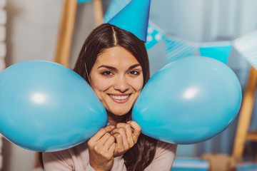 Fun during birthday. Joyful sweet woman holding balloons while grinning to camera