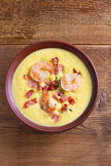 Creamy corn vegetable soup with shrimps and bacon. View from above, top studio shot