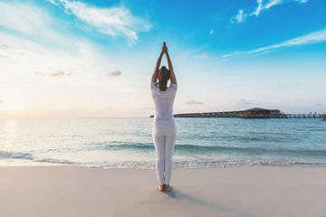 Schilderijen op glas Asian woman practicing yoga Lotus pose on the beach in Maldives at sunset,Feeling so comfortable and relax in holiday,Healthy Concept © 220 Selfmade studio