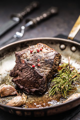 Juicy beef steak with spices and herbs in old pan