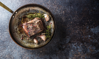 Fototapeta na wymiar Juicy beef steak with spices and herbs in old pan