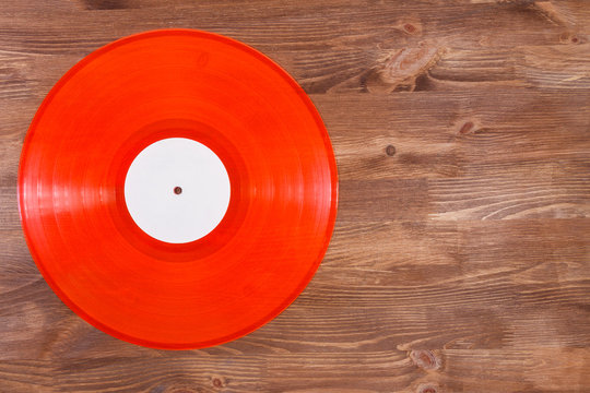 Red color vinyl record on brown wooden background