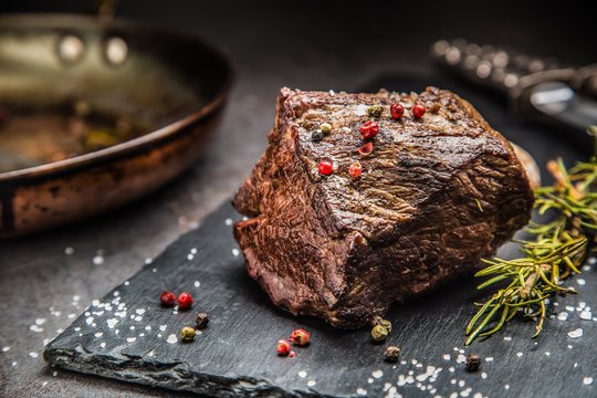 Juicy beef steak with spices and herbs on cutting board