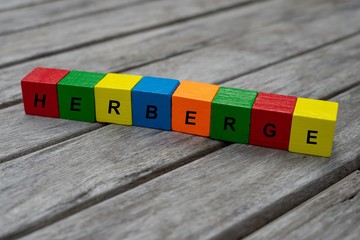 Farbige Holzwürfel mit Buchstaben auf dem das Wort Herberge abgebildet ist, Abstrakte Illustration