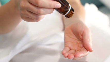 Closeup slow motion video of lots of red pills falling on hand of sick woman lying in bed - Powered by Adobe