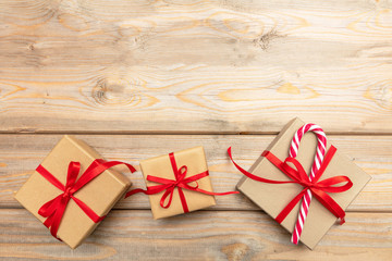 Gift boxes with red ribbon and candy cane on wooden background, copy space, top view