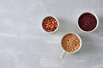 various dried beans with kitchen utensils on gray table, top view