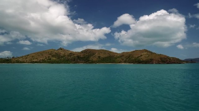Fahrt mit Blick auf eine Insel mit vorbeifahrendem Motorboot