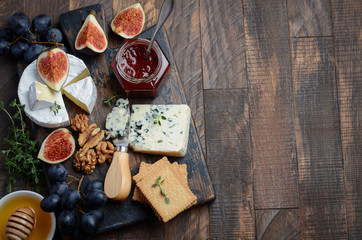 Cheese plate with grapes, figs, crackers, honey, plum jelly, thyme and nuts, top view, copy space. - Powered by Adobe