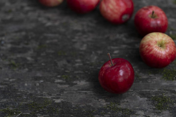 Red apples on an old wooden surface  covered with moss here and there. Red apples on an dark old wooden table.