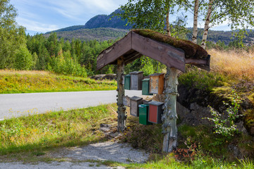 Colorful post boxes near the road under traditional wooden norwegian shed with green moss on the...