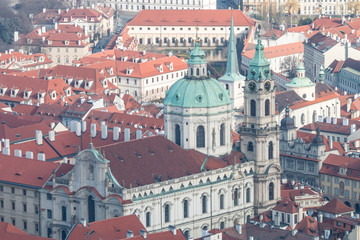 Fototapeta na wymiar View of winter Prague. Beautiful cityscape with classic red roofs and Church of St. Nicholas.